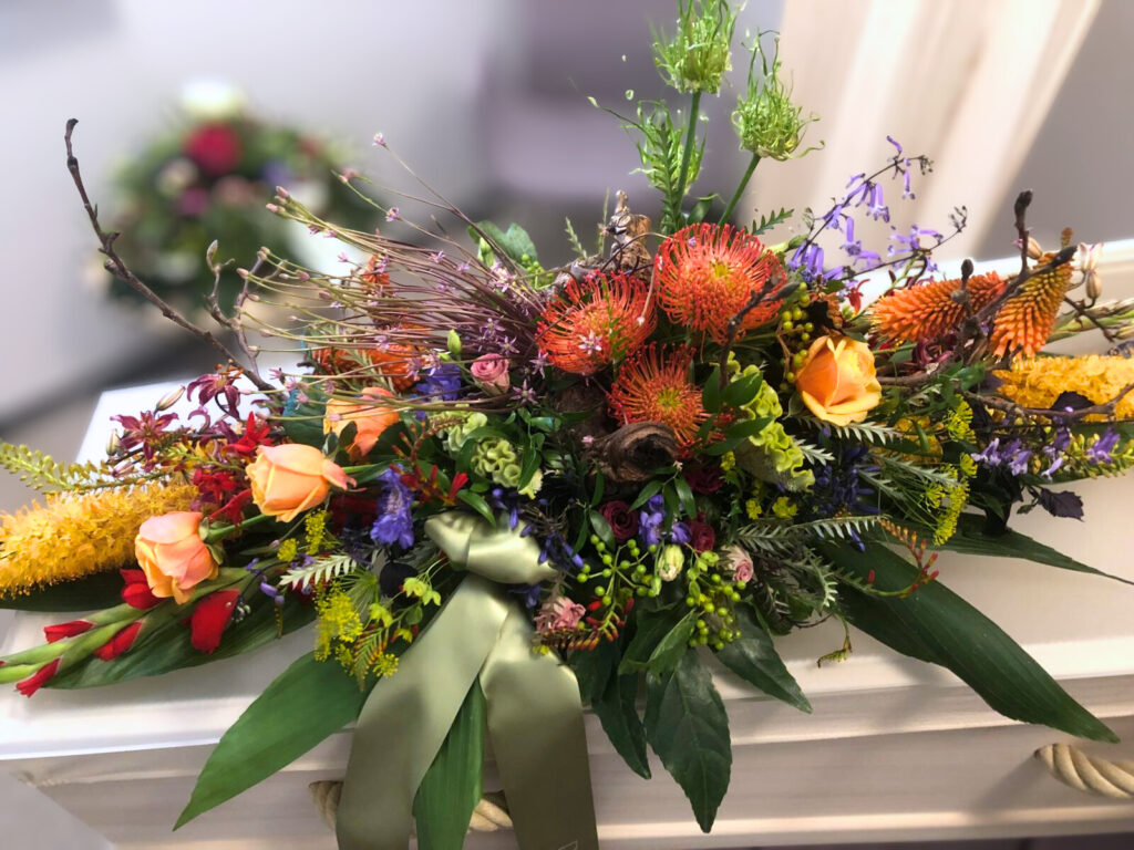 Rouwbloemstuk met kleurrijke bloemen op een kist