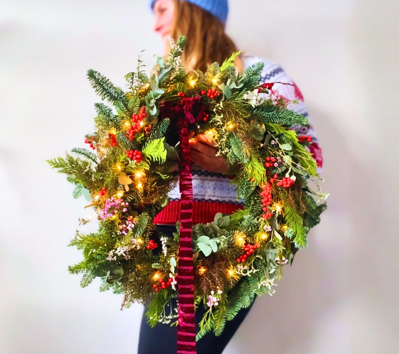 Kerstkrans met verschillende soorten groen, bessen en lichtjes