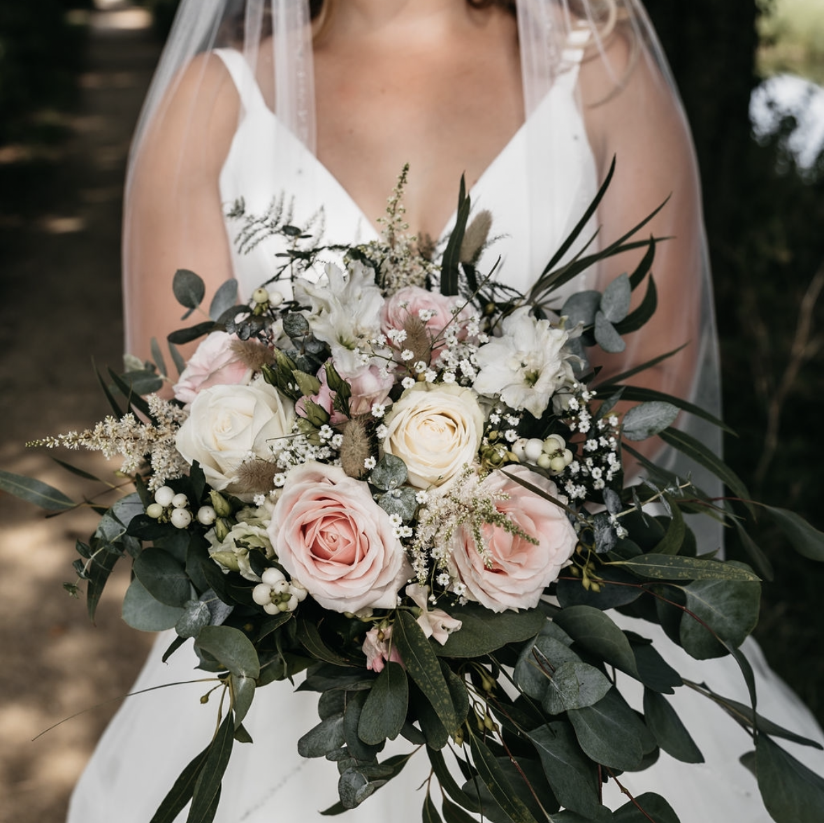 Bruidsboeket met roze en witte rozen, eucalyptus, bessen en gipskruid.