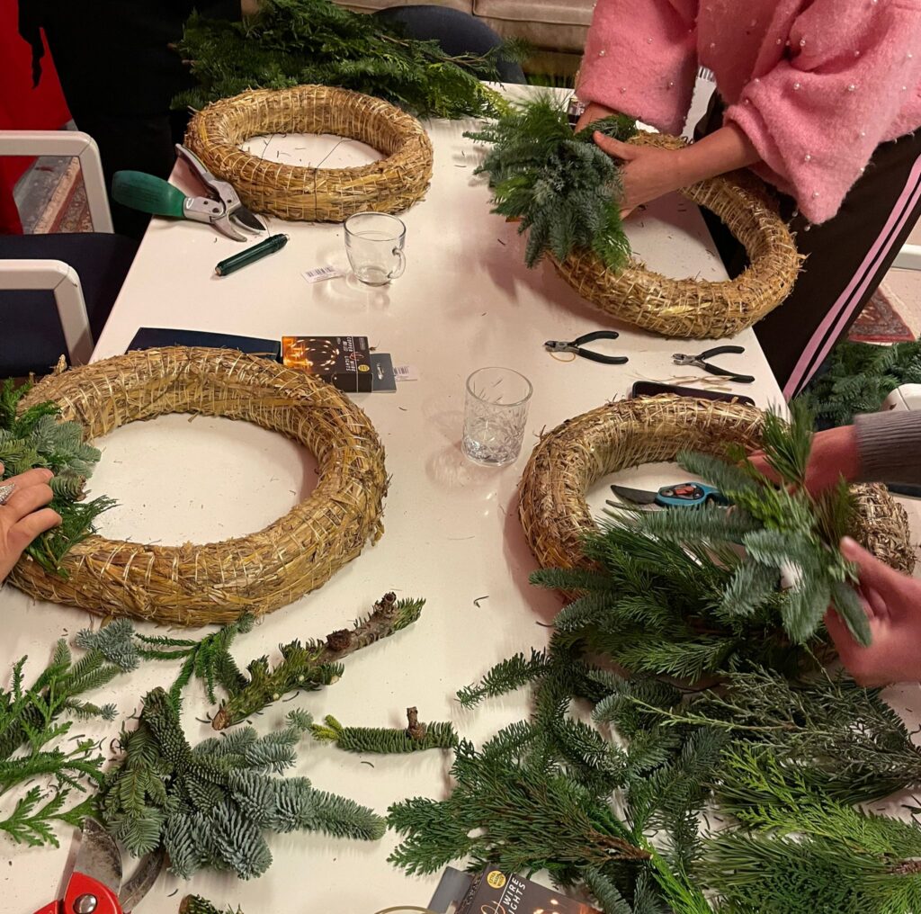 Een deelnemer maakt een kerstkrans van kerstgroen,  kerstworkshop Bloom & Beyond Reeuwijk